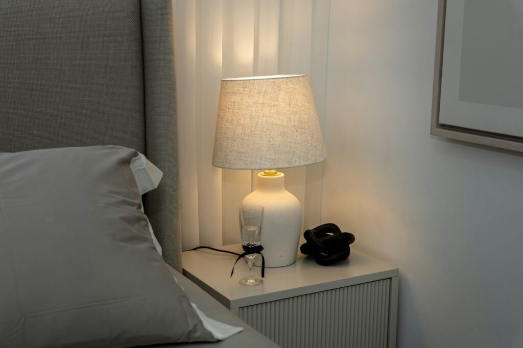 Warm bedside lamp next to grey pillows