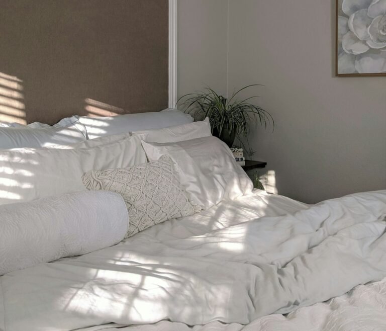 Sunlit bed with white linen sheets